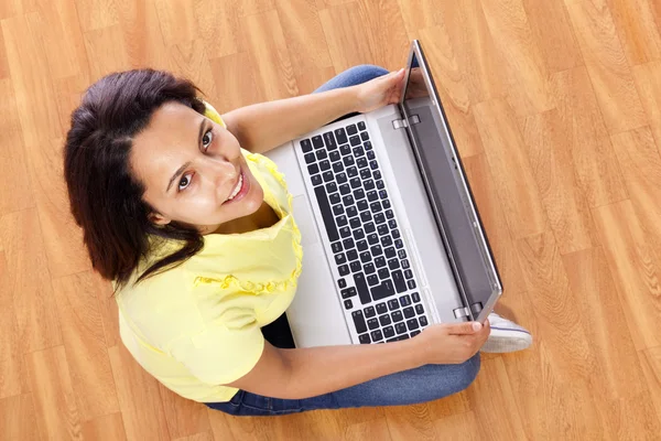 Bella donna seduta sul pavimento e che lavora con un computer portatile a casa — Foto Stock