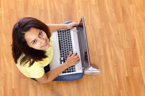 Schöne Frau, die auf dem Boden sitzt und zu Hause mit einem Laptop arbeitet — Stockfoto