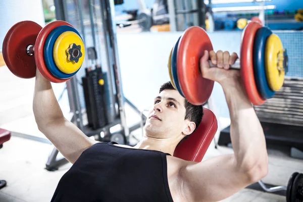 Homme fort s'entraînant avec des poids dans la salle de gym — Photo