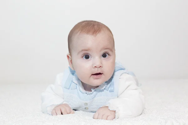 Aranyos baba feküdt a fehér takaró, és mosolyogva — Stock Fotó
