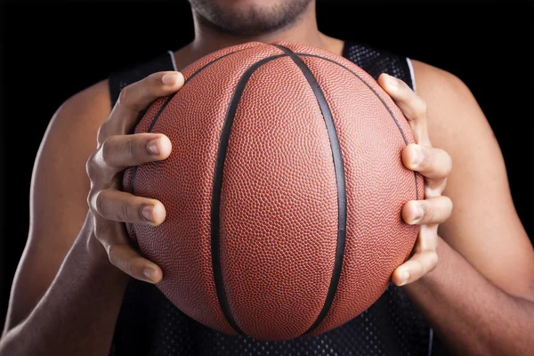 Jogador de basquete segurando uma bola contra fundo escuro — Fotografia de Stock