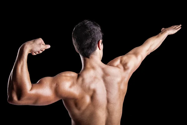 Muscolo giovane uomo mostrando i muscoli della schiena contro un backgro scuro — Foto Stock