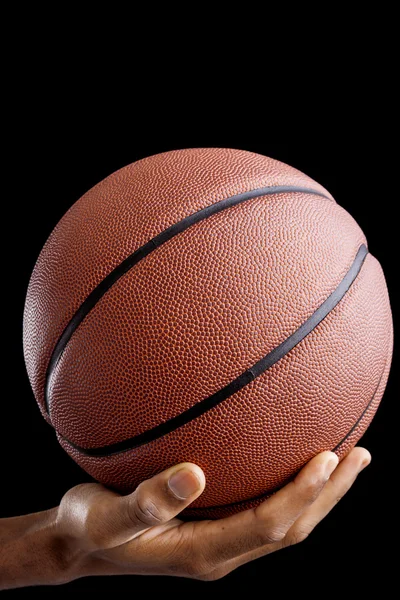 Basketbalový hráč držící míč proti tmavému pozadí — Stock fotografie