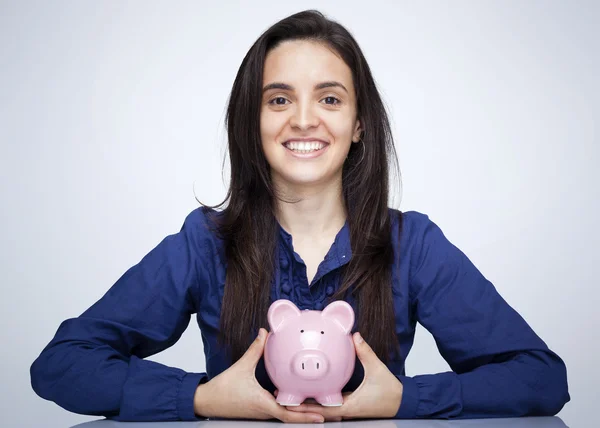 Glücklich lächelnde Frau mit Sparschwein vor grauem Hintergrund — Stockfoto