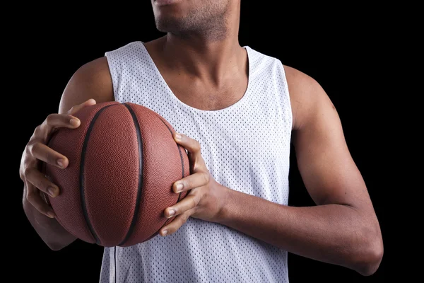 在黑暗的背景下举行一个球的篮球运动员 — 图库照片