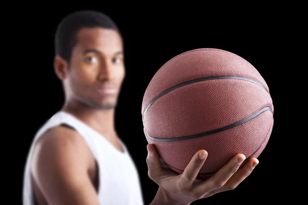 Jugador de baloncesto sosteniendo una pelota contra fondo oscuro — Foto de Stock