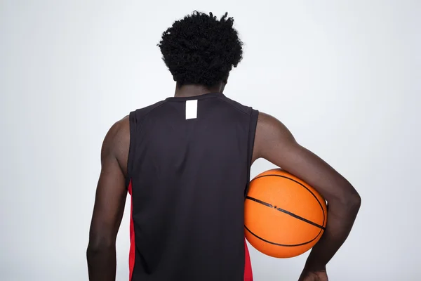 Achteraanzicht van een basketbalspeler met een bal tegen grijze bac — Stockfoto