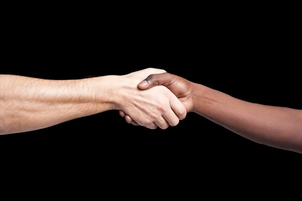 Handshake between african and a caucasian man against dark backg — Stock Photo, Image