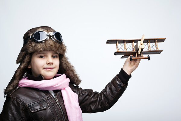 Happy child playing with toy airplane against gray background