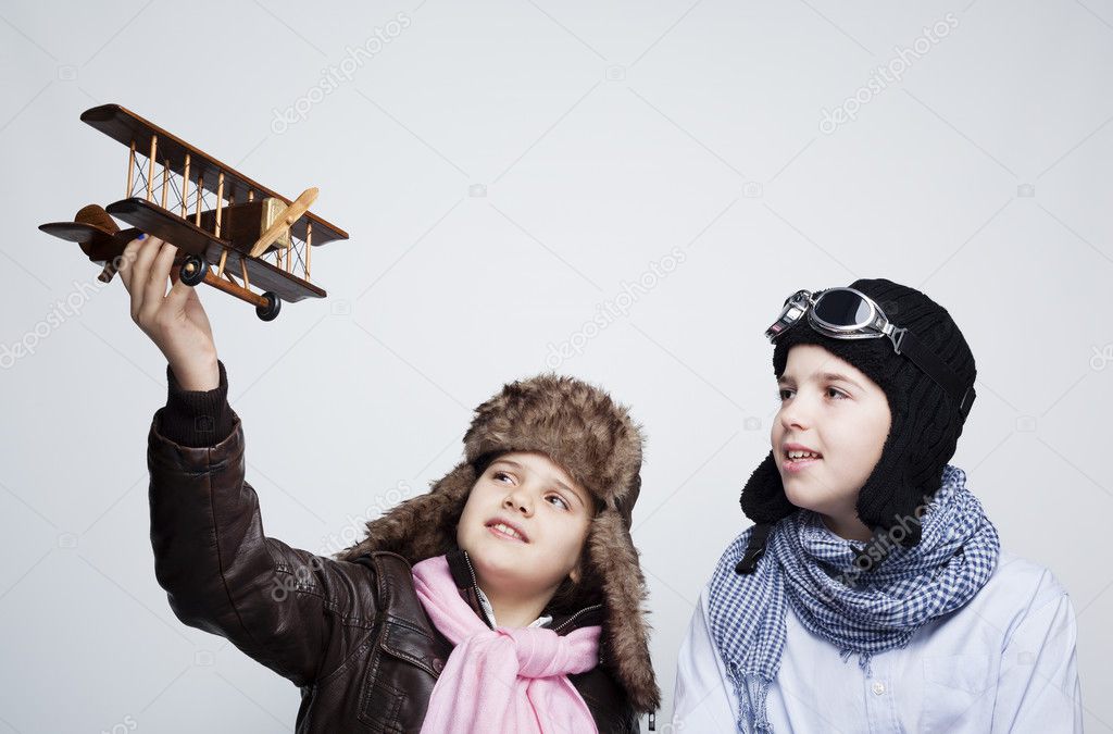 Happy kids playing with toy airplane against gray background