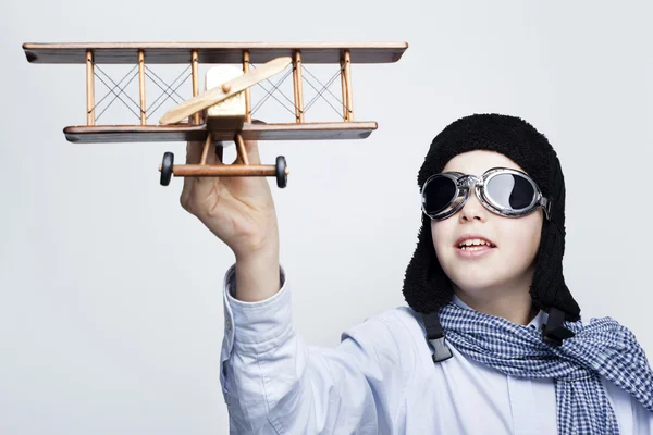 Gelukkig kind spelen met speelgoed vliegtuig tegen de grijze achtergrond — Stockfoto