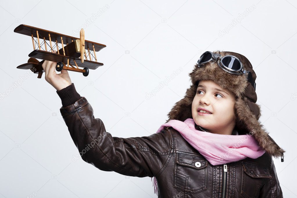 Happy child playing with toy airplane against gray background