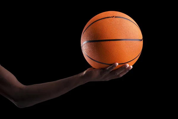 Jugador de baloncesto sosteniendo una pelota contra fondo oscuro — Foto de Stock