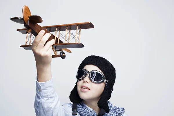 Счастливый ребенок играет с игрушечным самолетом на сером фоне — стоковое фото