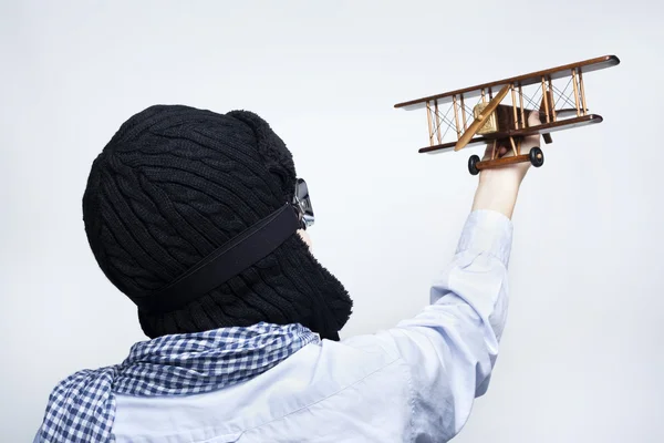 Bakifrån om ett barn leker med leksak flygplan mot grå bakgrunds — Stockfoto