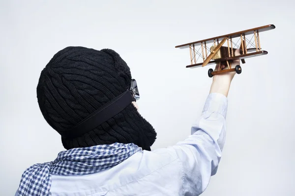 Vista trasera de un niño jugando con avión de juguete contra backgr gris — Foto de Stock