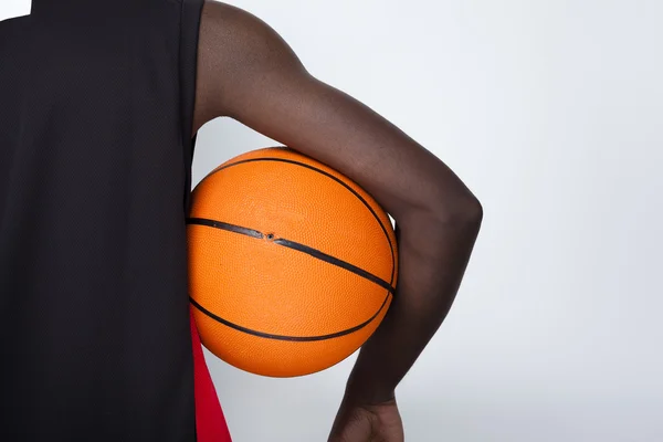 Vista trasera de un jugador de baloncesto sosteniendo una pelota contra bac gris —  Fotos de Stock