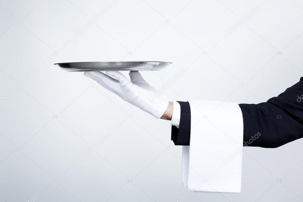 Waiter holding empty silver tray over gray background