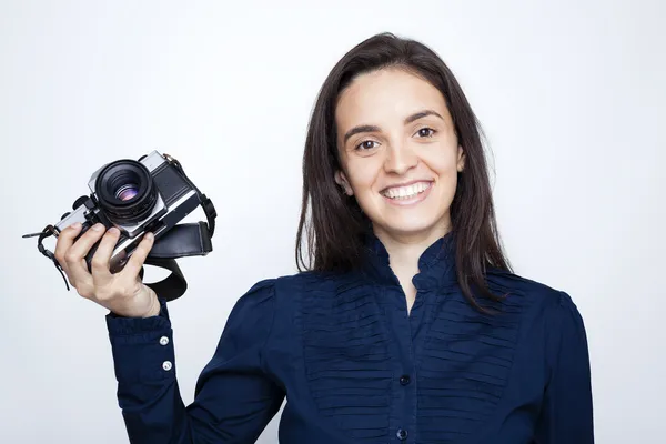 Woman photographer holding a camera over gray background — Stock Photo, Image