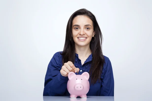 Empresária inserindo moeda em um banco porquinho — Fotografia de Stock