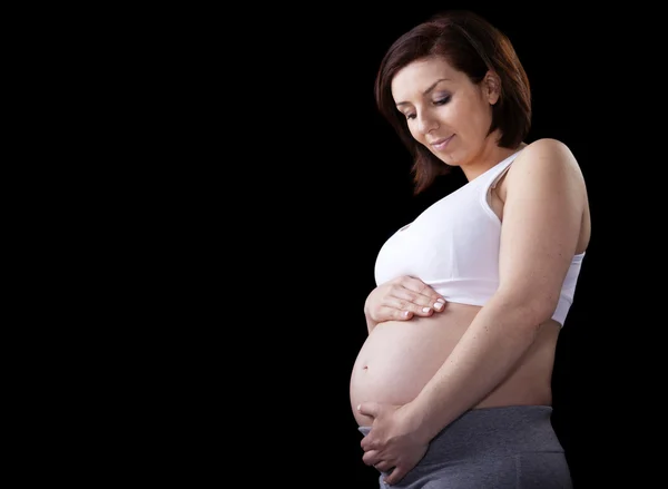 Schöne schwangere Frau vor schwarzem Hintergrund — Stockfoto