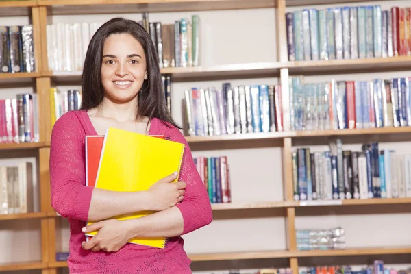 Glückliche Studentin mit Büchern in der Bibliothek — Stockfoto