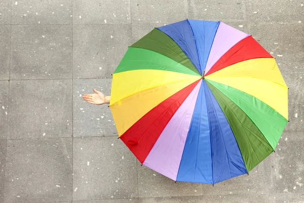 Mujer escondida bajo paraguas multicolor y comprobando si es ra — Foto de Stock