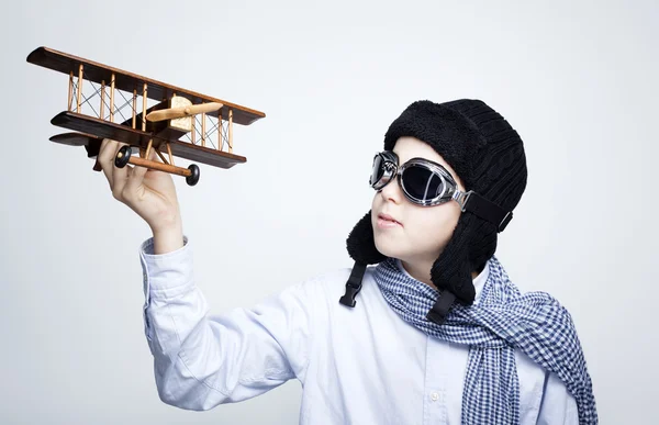 Criança feliz brincando com avião de brinquedo contra fundo cinza — Fotografia de Stock