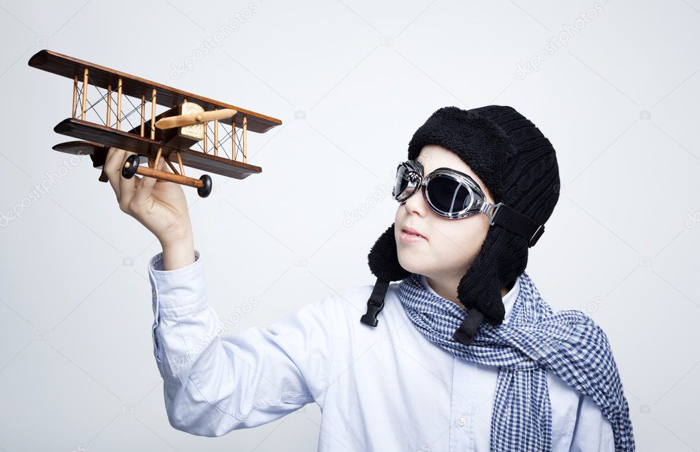 Happy kid playing with toy airplane against gray background