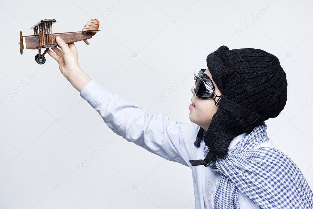 Happy kid playing with toy airplane against gray background