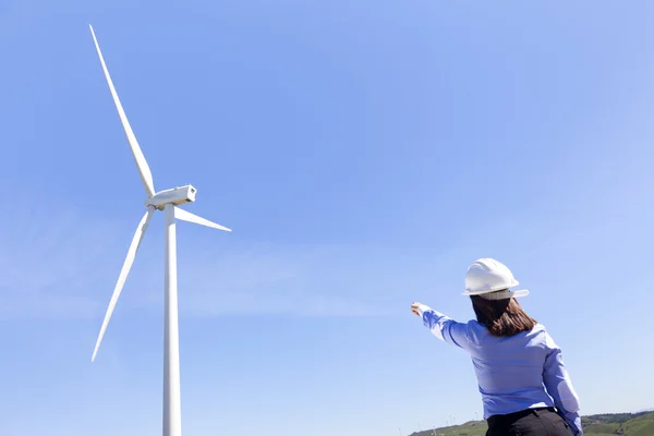 Ingénieur pointant vers un moulin à vent dans un parc éolien — Photo