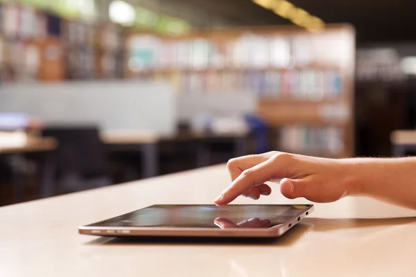 Hand typing on tablet pc in library — Stock Photo, Image