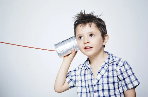 Niño feliz usando una lata como teléfono contra fondo gris —  Fotos de Stock