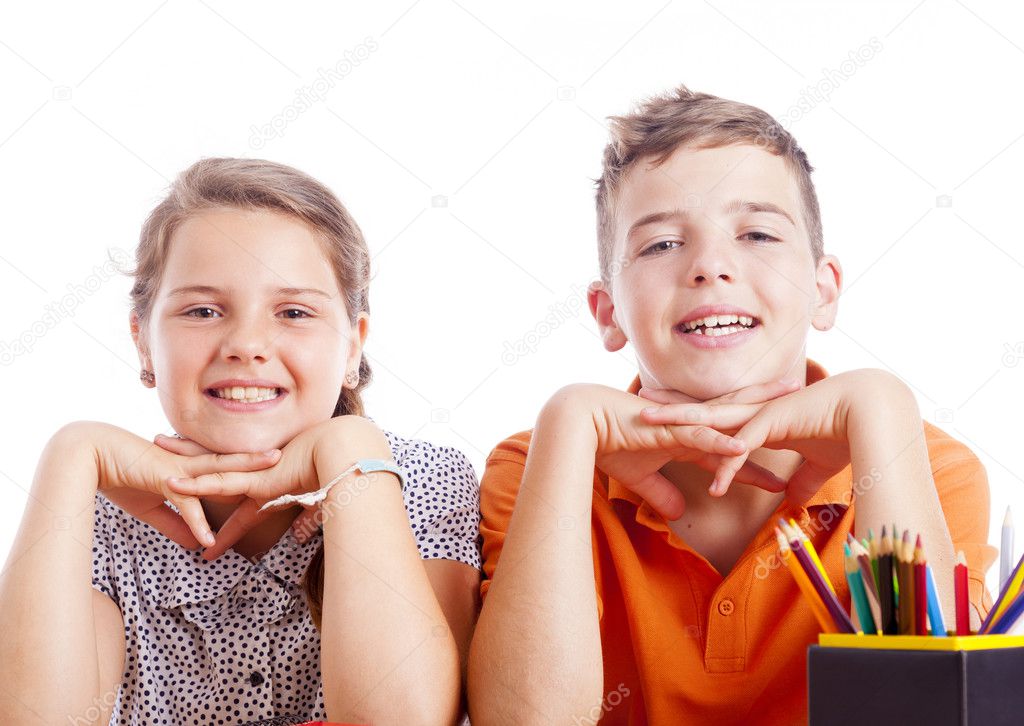Portrait of two school kids at the desk, isolated on white backg