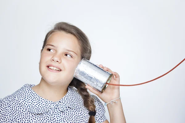 Glücklich lächelndes Kind mit einer Dose als Telefon gegen grauen Backgr — Stockfoto