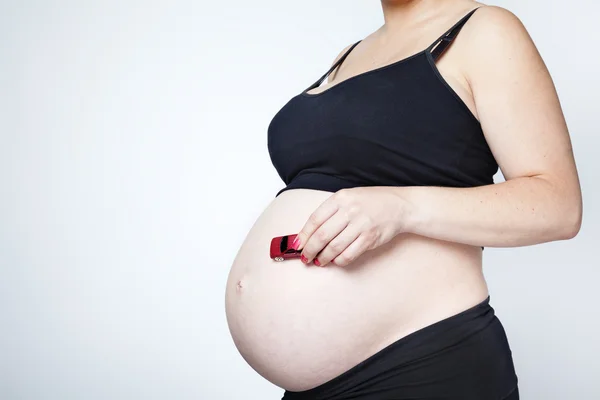 Pregnant woman holding a toy car in her belly — Stock Photo, Image