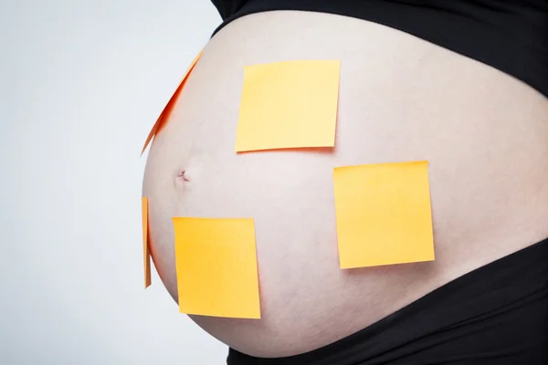 Schwangerschaftsbauch mit gelben Stöcken — Stockfoto