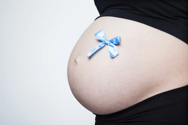 Schwangerer Bauch mit blauer Schleife — Stockfoto