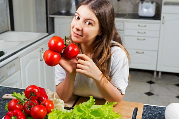 Young woman with tomato standing at kitchen — Stock Photo, Image