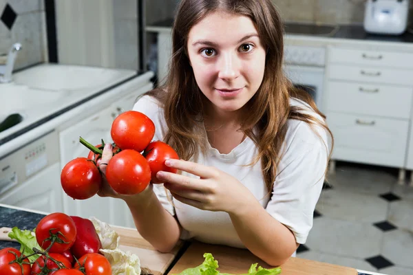 Young woman holding bunch of tomatoes — Stock Photo, Image