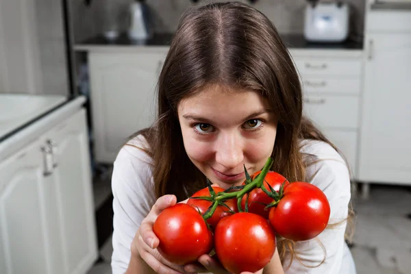 Mujer joven con primer plano de tomate en la cocina — Foto de Stock