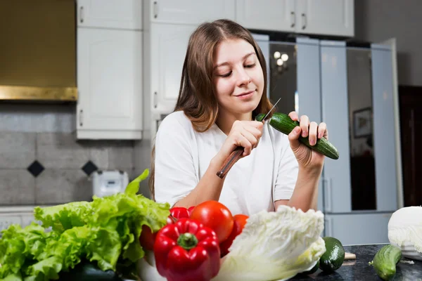 Mujer joven en cocina corte pepino — Foto de Stock