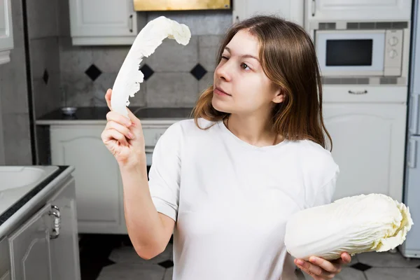 Mujer joven en la cocina mirando ensalada — Foto de Stock