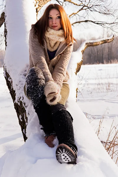 Roztomilá blondýna sedí ve winter parku, slunečný den. — Stock fotografie