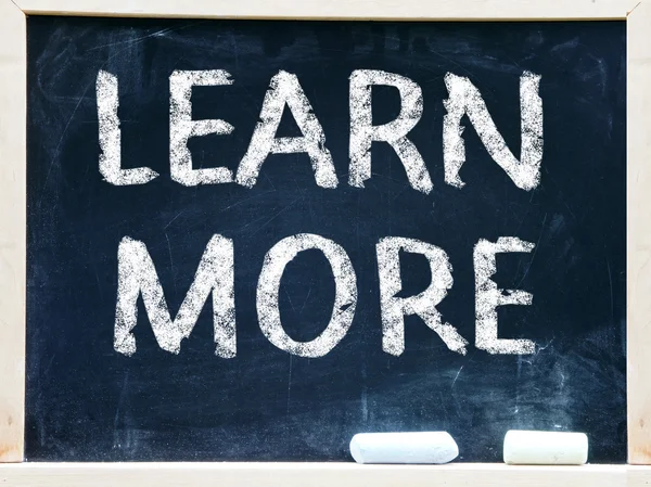 "Learn More" handwritten with white chalk on a blackboard — Stock Photo, Image