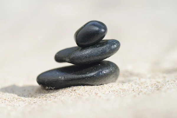 Zwarte stenen op het zand — Stockfoto