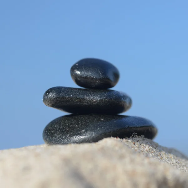 Zwarte stenen op het zand — Stockfoto