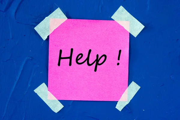 Pomoc! na růžovém lepící papír nalepený na modré zdi — Stock fotografie