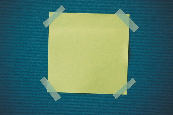 A blank sticky note with a notebook on the wall — Stock Photo, Image