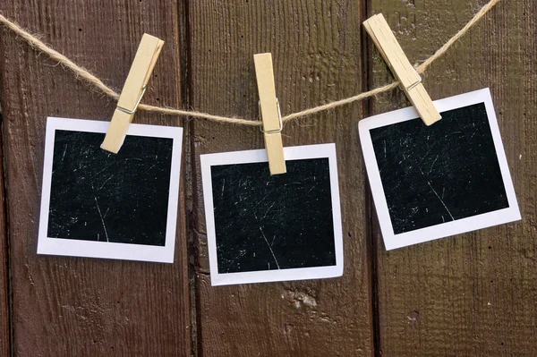 Papel fotográfico anexar à corda com pinos de roupas no fundo de madeira — Fotografia de Stock